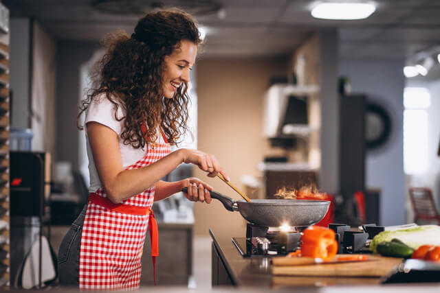 Mulher preparando refeição em fogão a gás